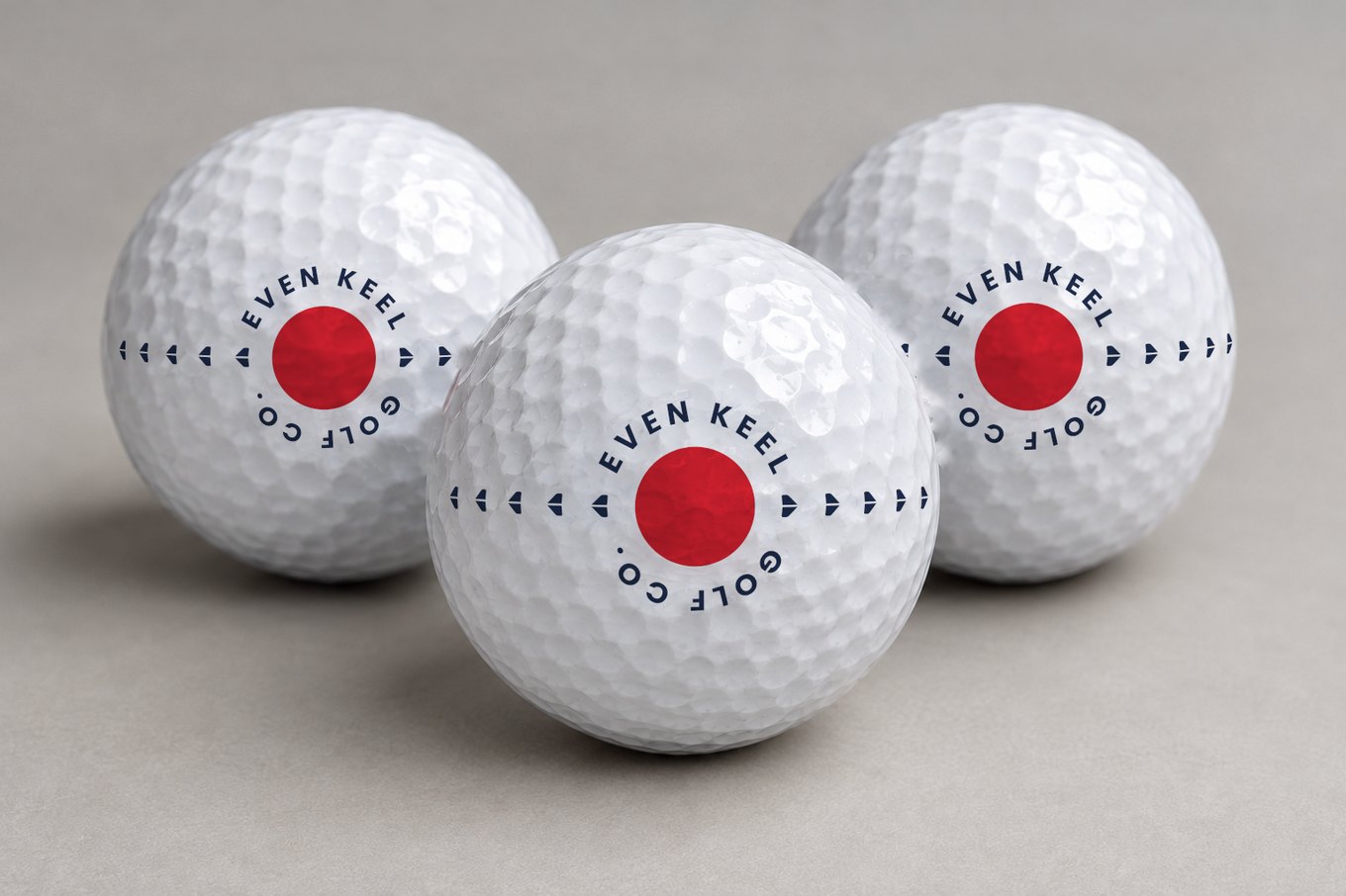 Three white golf balls, each printed with the Even Keel Golf Co. logo: a red dot ringed by the name, with navy arrows marking the balance line.